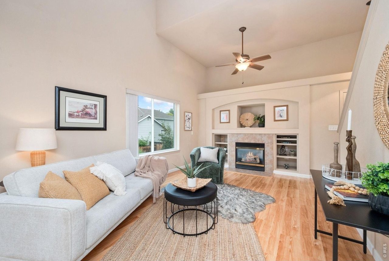 Living room with vaulted ceiling, gas fireplace, built-in shelving and large windows